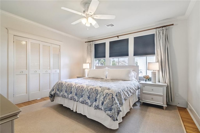 bedroom featuring hardwood / wood-style flooring, crown molding, ceiling fan, and a closet