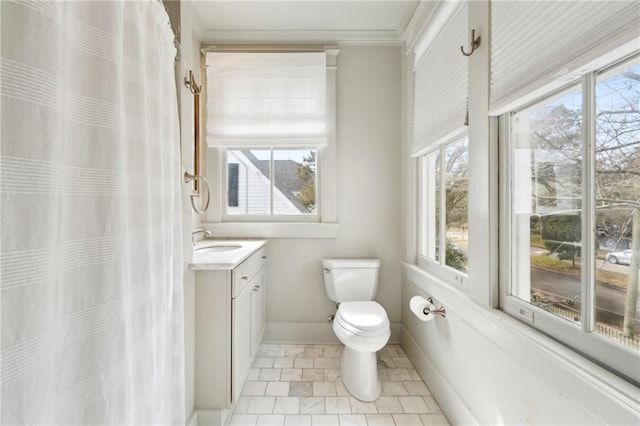 bathroom with ornamental molding, a healthy amount of sunlight, vanity, and toilet