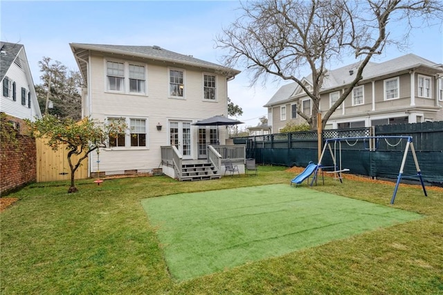 rear view of property featuring a playground, a wooden deck, and a yard