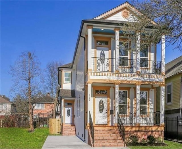 view of front facade featuring a front yard, a balcony, and a porch