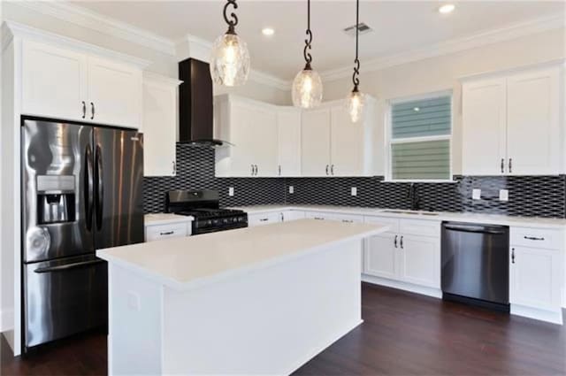 kitchen featuring appliances with stainless steel finishes, decorative light fixtures, white cabinets, a center island, and wall chimney range hood