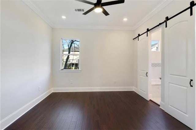 unfurnished bedroom featuring crown molding, ensuite bathroom, a barn door, and dark wood-type flooring