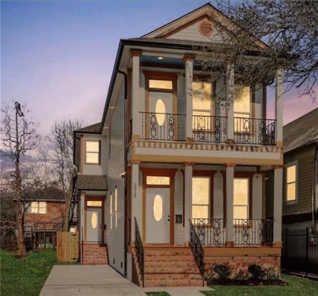 view of front of property with a balcony, a porch, and a lawn