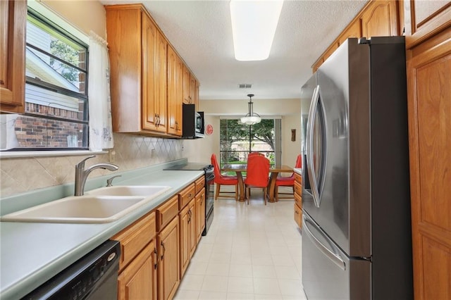 kitchen featuring sink, hanging light fixtures, black appliances, a textured ceiling, and decorative backsplash