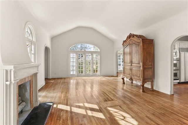 unfurnished living room featuring hardwood / wood-style flooring, a tiled fireplace, and vaulted ceiling