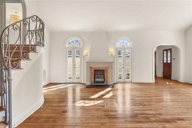 unfurnished living room with hardwood / wood-style floors, a wealth of natural light, and french doors