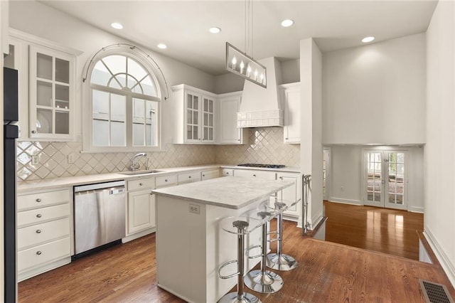 kitchen with appliances with stainless steel finishes, sink, white cabinets, hanging light fixtures, and a center island