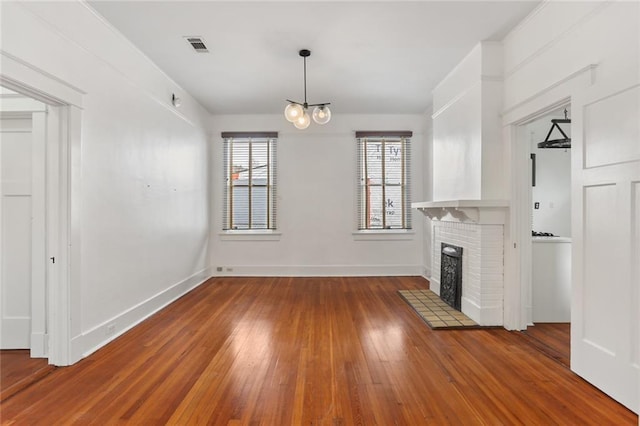 unfurnished living room featuring hardwood / wood-style flooring, a fireplace, and a chandelier