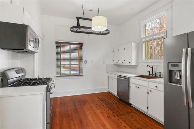 kitchen featuring sink, white cabinets, hanging light fixtures, stainless steel appliances, and a healthy amount of sunlight