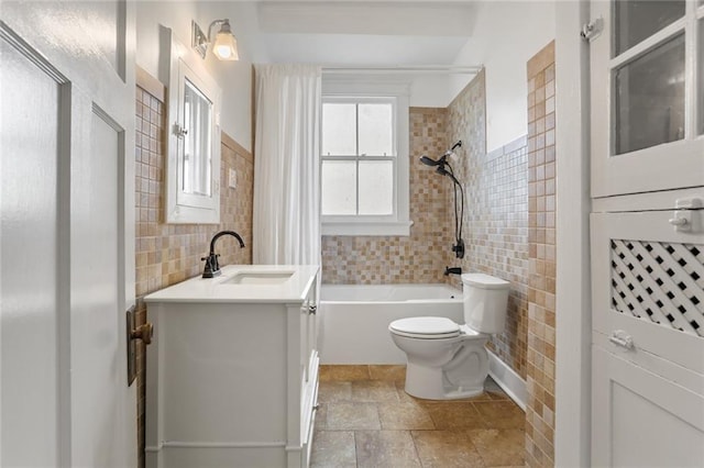 full bathroom featuring vanity, tiled shower / bath, tile walls, and toilet