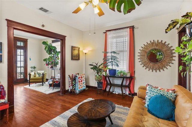 living area with dark wood-type flooring and ceiling fan