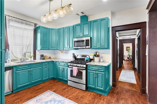 kitchen with hanging light fixtures, appliances with stainless steel finishes, sink, and dark wood-type flooring