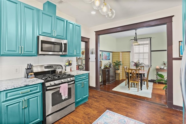 kitchen with pendant lighting, appliances with stainless steel finishes, light stone countertops, and blue cabinetry