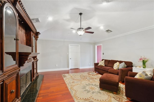 living room with crown molding, a fireplace, dark hardwood / wood-style floors, and ceiling fan