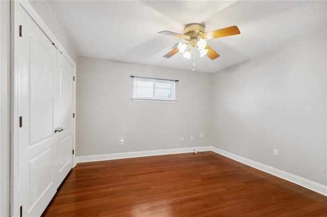 unfurnished bedroom with dark hardwood / wood-style flooring, a textured ceiling, a closet, and ceiling fan