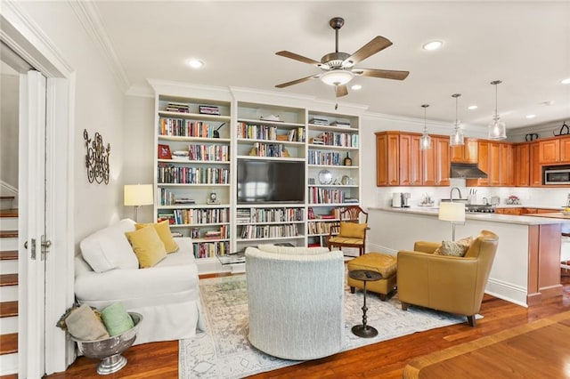 sitting room featuring wood-type flooring, ornamental molding, and ceiling fan