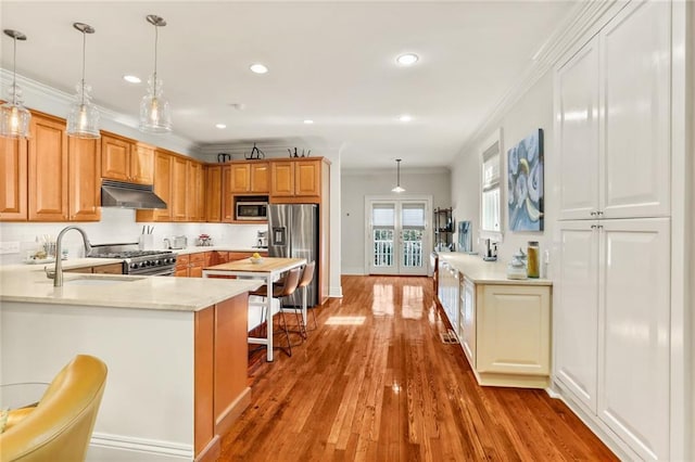 kitchen with pendant lighting, sink, a kitchen bar, kitchen peninsula, and stainless steel appliances