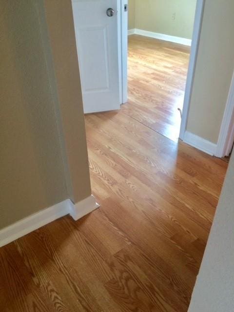 hallway with light wood-style flooring and baseboards