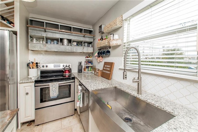 kitchen with light stone counters, appliances with stainless steel finishes, sink, and tasteful backsplash