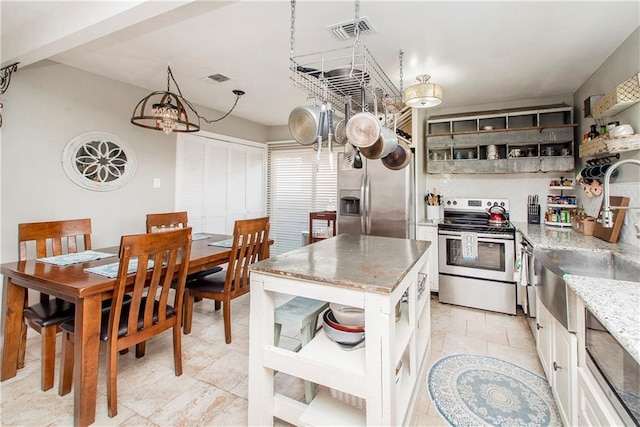 kitchen featuring a kitchen island, white cabinetry, sink, light stone counters, and stainless steel appliances