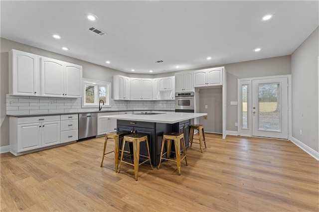 kitchen with stainless steel dishwasher, a breakfast bar, visible vents, and white cabinetry