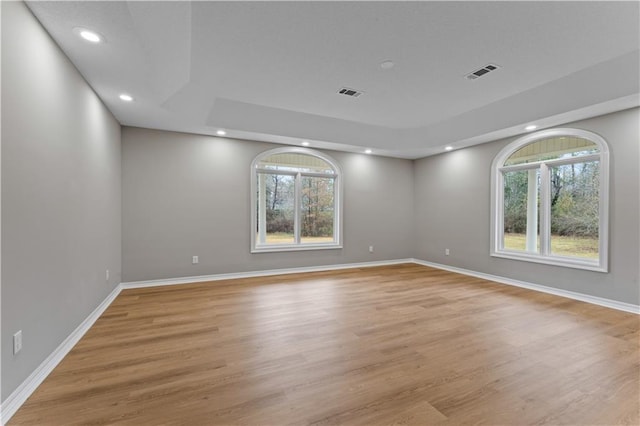 empty room with light wood-type flooring, visible vents, and baseboards