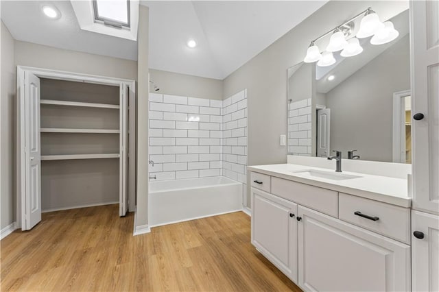 bathroom with wood finished floors, vaulted ceiling, vanity, shower / washtub combination, and recessed lighting