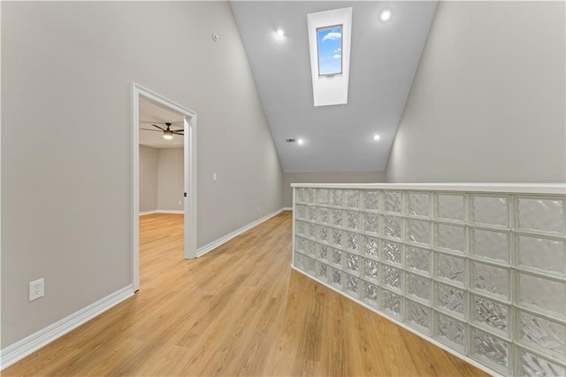 interior space featuring a skylight, light wood-style flooring, and baseboards