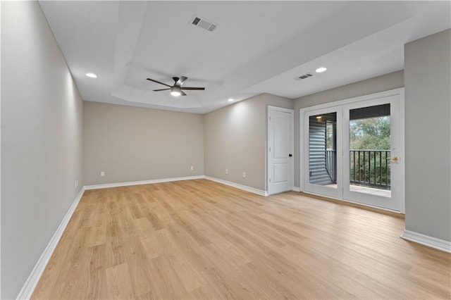 empty room with light wood-style floors, visible vents, and baseboards