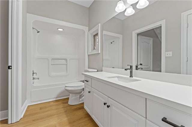 bathroom with toilet, washtub / shower combination, wood finished floors, and vanity