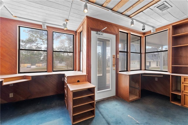 unfurnished office featuring rail lighting, carpet, wooden walls, and visible vents