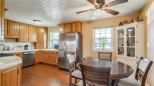 kitchen featuring backsplash, stainless steel appliances, tile countertops, and a wealth of natural light