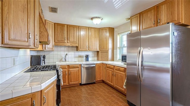 kitchen featuring dark wood-type flooring, sink, tile countertops, appliances with stainless steel finishes, and backsplash