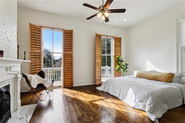 bedroom featuring multiple windows, access to exterior, dark wood-type flooring, and a high end fireplace