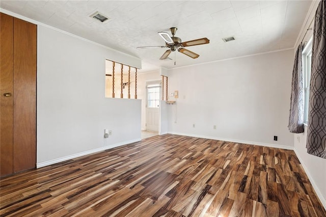 unfurnished room with crown molding, visible vents, a ceiling fan, wood finished floors, and baseboards