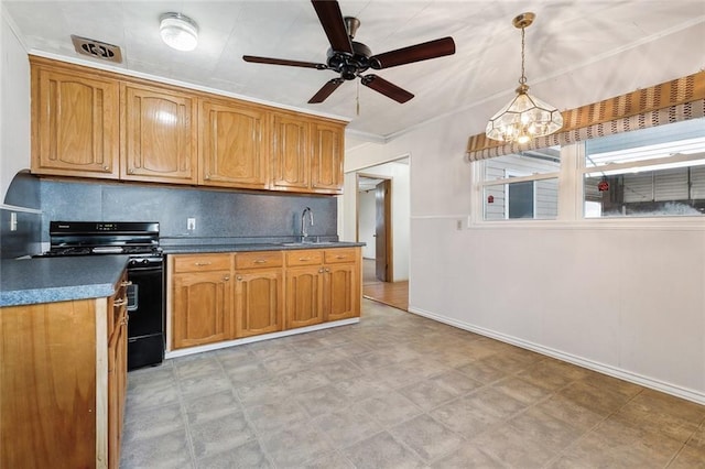 kitchen featuring dark countertops, black gas range oven, brown cabinets, decorative light fixtures, and a sink