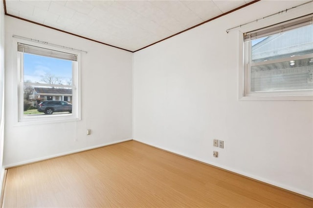 spare room featuring crown molding, baseboards, and wood finished floors