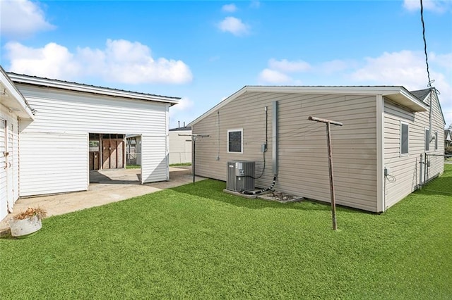 back of house with a lawn, metal roof, and central AC