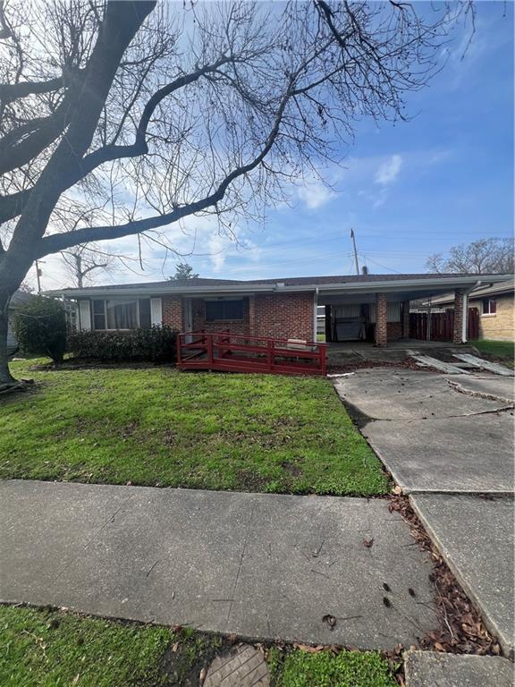 ranch-style home featuring a carport and a front lawn