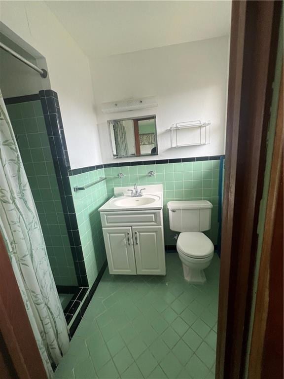 bathroom with vanity, toilet, a shower with shower curtain, and tile walls