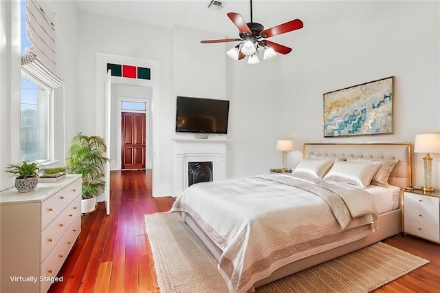 bedroom with ceiling fan, wood-type flooring, and a high ceiling