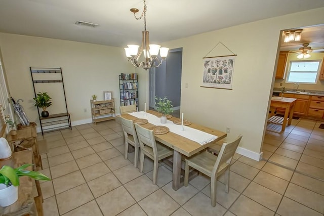 dining area with light tile patterned floors, ceiling fan with notable chandelier, and sink