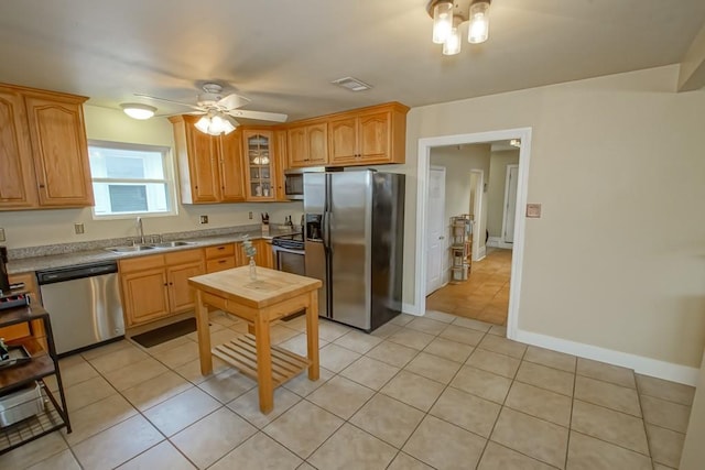 kitchen featuring light tile patterned flooring, ceiling fan, appliances with stainless steel finishes, and sink