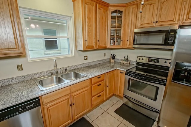 kitchen featuring appliances with stainless steel finishes, light stone countertops, sink, and light tile patterned floors