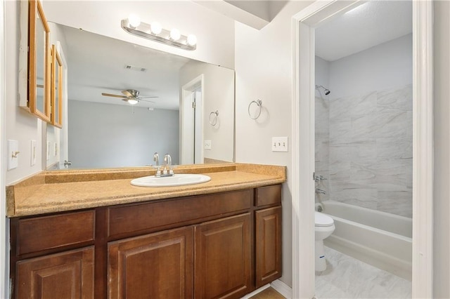 full bathroom with ceiling fan, vanity, toilet, and tiled shower / bath combo