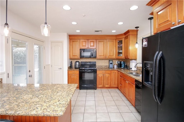 kitchen featuring pendant lighting, sink, light tile patterned floors, black appliances, and light stone countertops