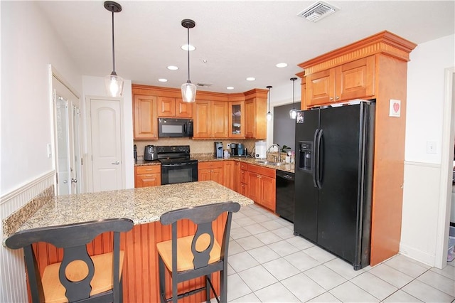 kitchen with pendant lighting, sink, a breakfast bar area, black appliances, and kitchen peninsula