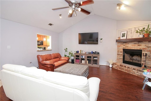 living room with dark wood-type flooring, ceiling fan, a fireplace, and vaulted ceiling