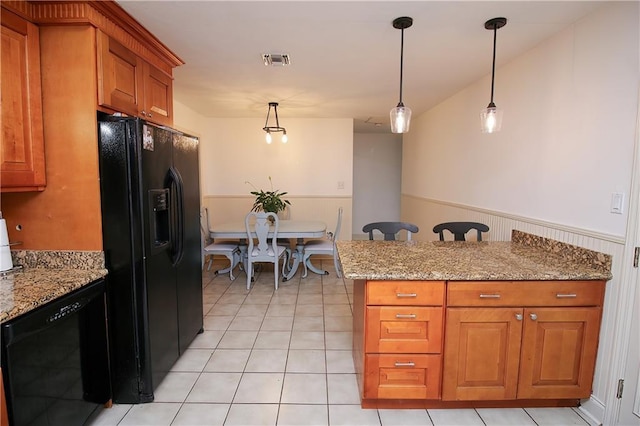 kitchen featuring pendant lighting, light stone countertops, light tile patterned floors, and black appliances