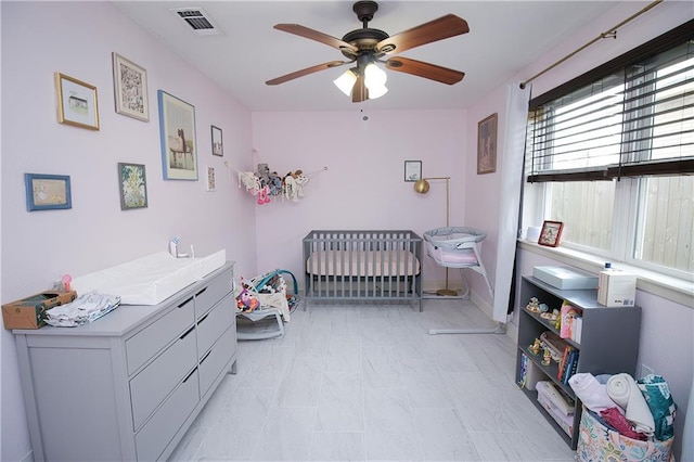 bedroom with ceiling fan and a crib